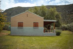 una casa in un campo con una montagna sullo sfondo di Vogelsang Farm Cottage a Oudtshoorn