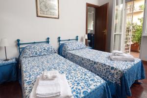 a bedroom with two beds with blue and white sheets at 2 Passi Da in Rome