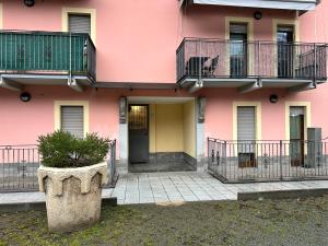een roze gebouw met een gele deur en een balkon bij Alvina's House in Aosta