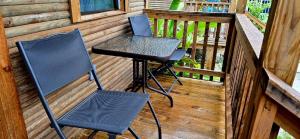 two chairs and a table on the porch of a cabin at Tuquil-HA in Ladyville