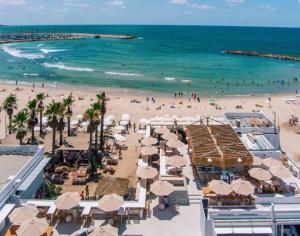a beach with umbrellas and people on the beach at Haim Arlosoroff Residence - MAMAD in Tel Aviv