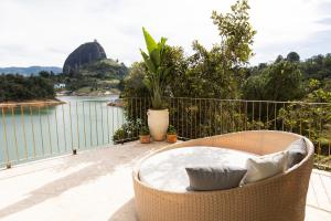 a rattan chair sitting on a balcony overlooking a body of water at MYLOS Hotel Boutique in Guatapé