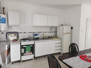 a kitchen with white cabinets and a stove and a table at Duplex en Gualeguay in Gualeguay +6 photos