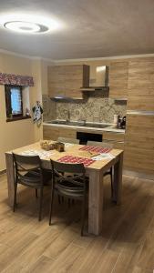 a kitchen with a wooden table with chairs and a kitchen counter at Appartamento ai piedi di Sestriere in Champlas du Col +11 photos