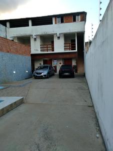 twee auto's geparkeerd op een parkeerplaats voor een gebouw bij Pousada Caribe Milagrense II in São Miguel dos Milagres