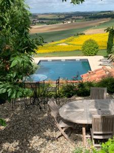 a table and chairs next to a swimming pool at Les 5 terrasses - vue imprenable et piscine privée in La Sauvetat