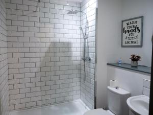 a white bathroom with a shower and a toilet at Spacious and Modern Studio Apartment Swansea City Centre in Swansea