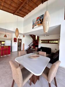Casa Dendê - Arraial D'Ajuda في ارايال دايودا: غرفة طعام وغرفة معيشة مع طاولة وكراسي بيضاء