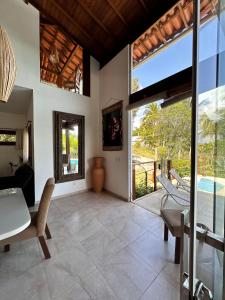 Casa Dendê - Arraial D'Ajuda في ارايال دايودا: غرفة معيشة مفتوحة مع طاولة وكراسي