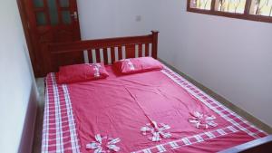 a pink bed with pink sheets and pillows on it at The Nightingales in Dickwella
