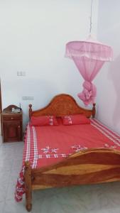 a bedroom with a wooden bed with a red bedspread at The Nightingales in Dickwella