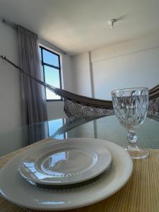 a glass table with a plate and a wine glass at Corais de Cotovelo in Parnamirim