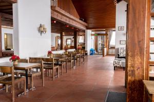 a restaurant with wooden ceilings and tables and chairs at Berghotel Pischa Mountain Lodge in Davos