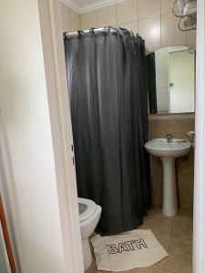 a bathroom with a black shower curtain and a toilet at CerroSur in Yacimiento Río Turbio