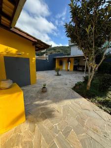 un patio con un edificio amarillo y un árbol en Casa piscina com hidromassagem, en Porto Belo