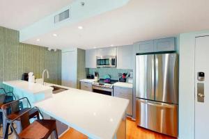 a kitchen with a stainless steel refrigerator and white cabinets at Cat Island Suite - Sunrise Suites in Key West