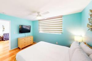 a blue bedroom with a bed and a tv at Cat Island Suite - Sunrise Suites in Key West +21 photos