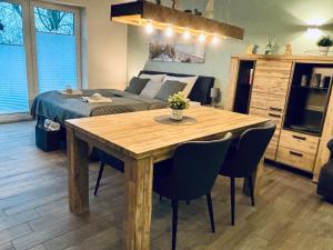 a living room with a wooden table and a bed at Kleine Auszeit -- inklusive Parkplatz & WiFi, Geschirrspüler, Waschmaschine & Terrasse mit Strandkorb -- Perfekt für Urlaub & Business in Scharbeutz
