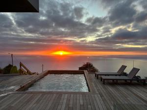 una piscina en una terraza con una puesta de sol en el fondo en Villa MARIE, en Fajã da Ovelha
