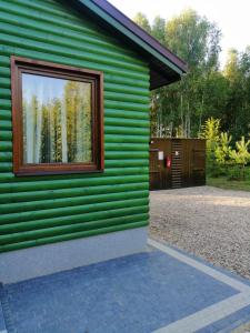 una casa verde con una finestra sul lato di Agroturystyka Klimaty Poleskiego Parku a Cyców