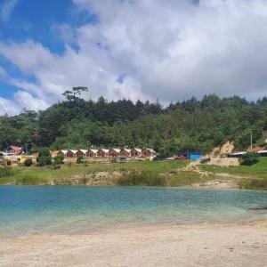 a group of houses on a hill next to a body of water at Cabañas la frontera in Santiago +3 photos