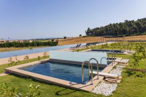 a large swimming pool in the middle of a field at Oikos Sani Suites in Sani Beach