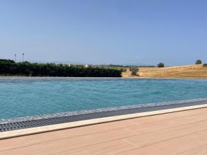 a swimming pool with blue water and a wooden deck at Oikos Sani Suites in Sani Beach