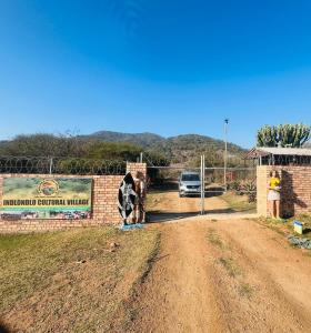un panneau avec une vache à côté d'un chemin de terre dans l'établissement Indlondlo Cultural Village, à Cato Ridge