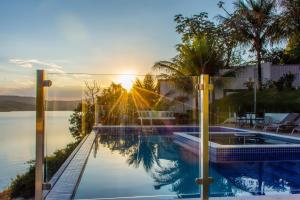 a swimming pool with the sun setting over the water at Hotel Boutique Coração Aberto in Capitólio