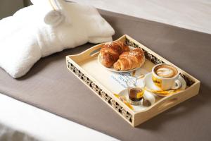 a tray with croissants and a cup of coffee on a bed at Napolitano Rooms - POMPEI in Pompei