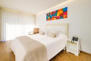 a white bedroom with a large white bed and a telephone at CANTINHO D'AVÓ - Apúlia in Areia