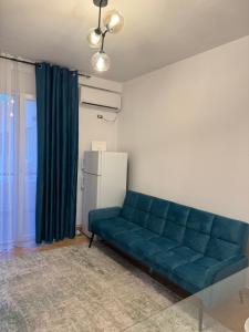 a blue couch in a living room with a window at Beach Front Superior Apartment Green forest in Durrës