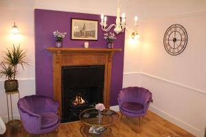 a living room with two purple chairs and a fireplace at St Margaret's Hotel in Oxford