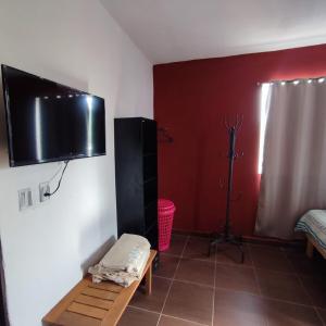 Ein Zimmer mit einem Fernseher an der Wand und einer Bank in der Unterkunft Casa texcoco in Cabo San Lucas