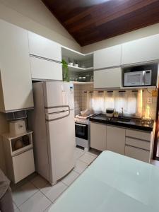 Una cocina con gabinetes blancos y un refrigerador. en Flat monte castelo condomínio, en Bezerros