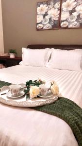 a tray with two cups and flowers on a bed at Family's home Trikala in Tríkala