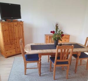 a wooden dining room table with chairs and a television at Monteurwohnung Sendberg Blick in Frielendorf +3 photos