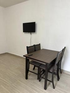 a dining room table with chairs and a television on a wall at Apartamentos la medero 4 in Nuevo Laredo +7 photos