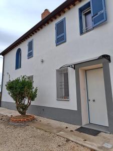 a white house with a door and a tree at Casa LaSer in Cotignola
