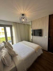 a bedroom with a large white bed and a chandelier at La perle du carrousel in Rabat +18 photos