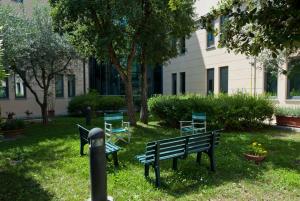 two park benches sitting in the grass in front of a building at L'incanto Di Boccadarno in Marina di Pisa