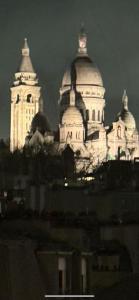 a view of a building with two towers at night at Studio avec vue sur Sacré-Coeur in Paris