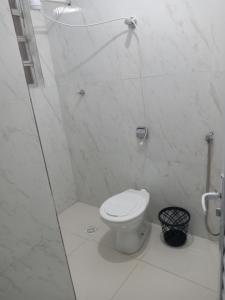 a white bathroom with a toilet and a shower at Casa com vista para o mar! in Peruíbe +1 photo