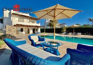 a patio with chairs and an umbrella next to a pool at Stylish 4 BR with a Private Heated Pool V15 at White Villas in Hurghada
