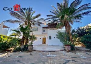 a house with two palm trees in front of it at Stylish 4 BR with a Private Heated Pool V15 at White Villas in Hurghada
