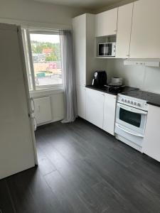 une cuisine avec des placards blancs, une fenêtre et une cuisinière dans l'établissement CHARLISE APARTMENTs, à Oslo