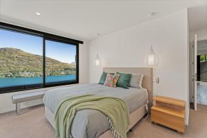 Un dormitorio con una cama y una ventana grande. en Lake Panorama - Queenstown Holiday Home, en Queenstown
