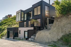 una casa negra en la cima de una colina en Lake Panorama - Queenstown Holiday Home, en Queenstown