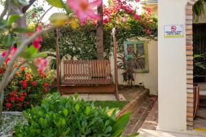 a wooden bench in a garden with flowers at Pousada Villa Tomasi in Jericoacoara