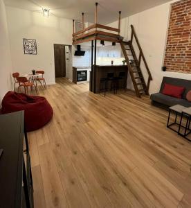 een woonkamer met een houten vloer en een trap bij Hola Apartamenty Rewolucji 1905r in Łódź